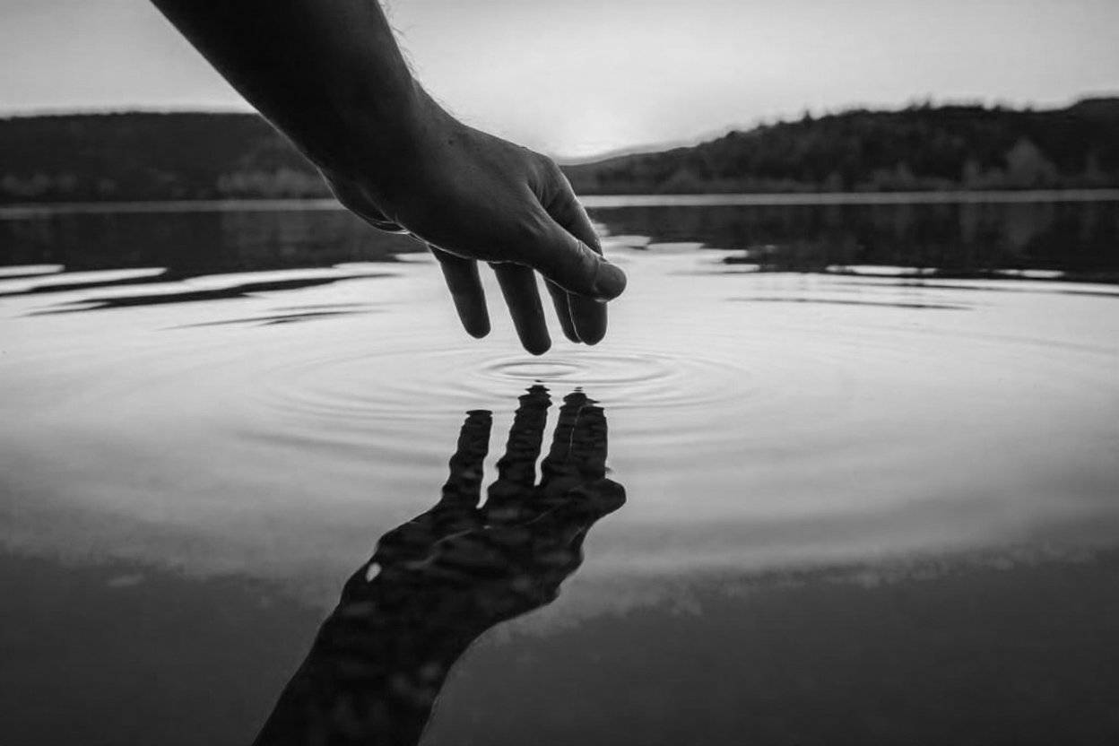 Hands reaching over water - connection and communication